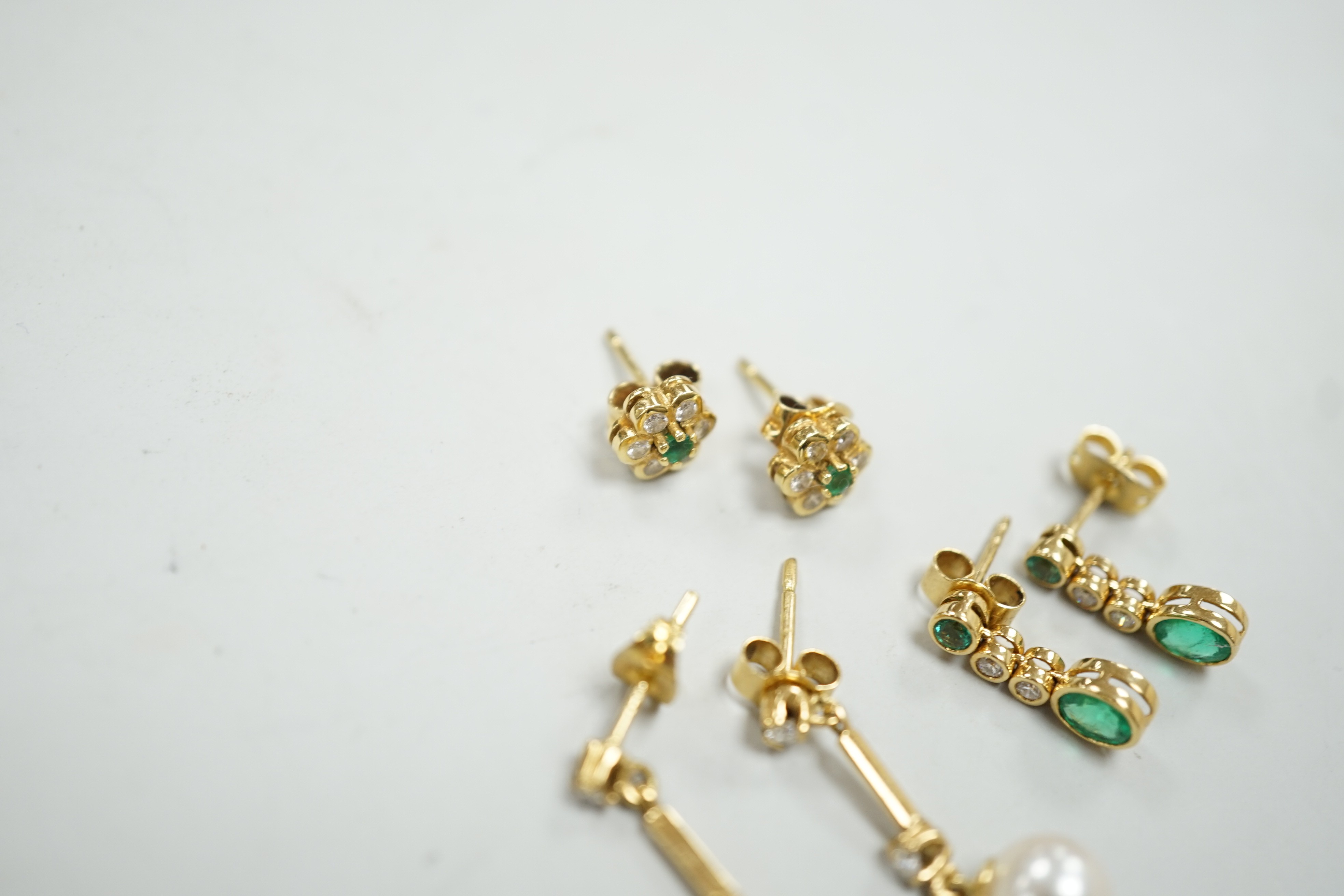 Two modern pairs of 18ct gold, emerald and diamond set ear studs and a pair of 18ct gold, cultured pearl and diamond set ear studs, gross weight 7 grams.